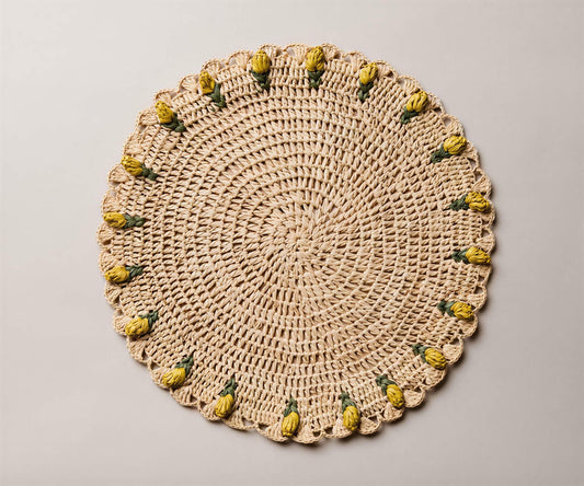 Handmade raffia crochet placemat featuring yellow tulip accents on a round, natural fiber design.