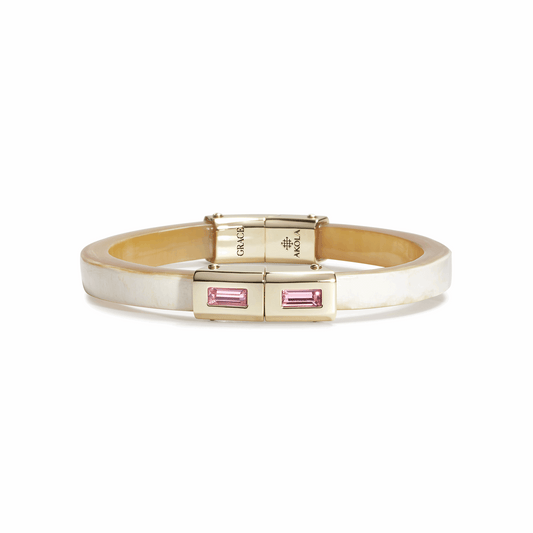 Gold bracelet with pink gemstones on a white background