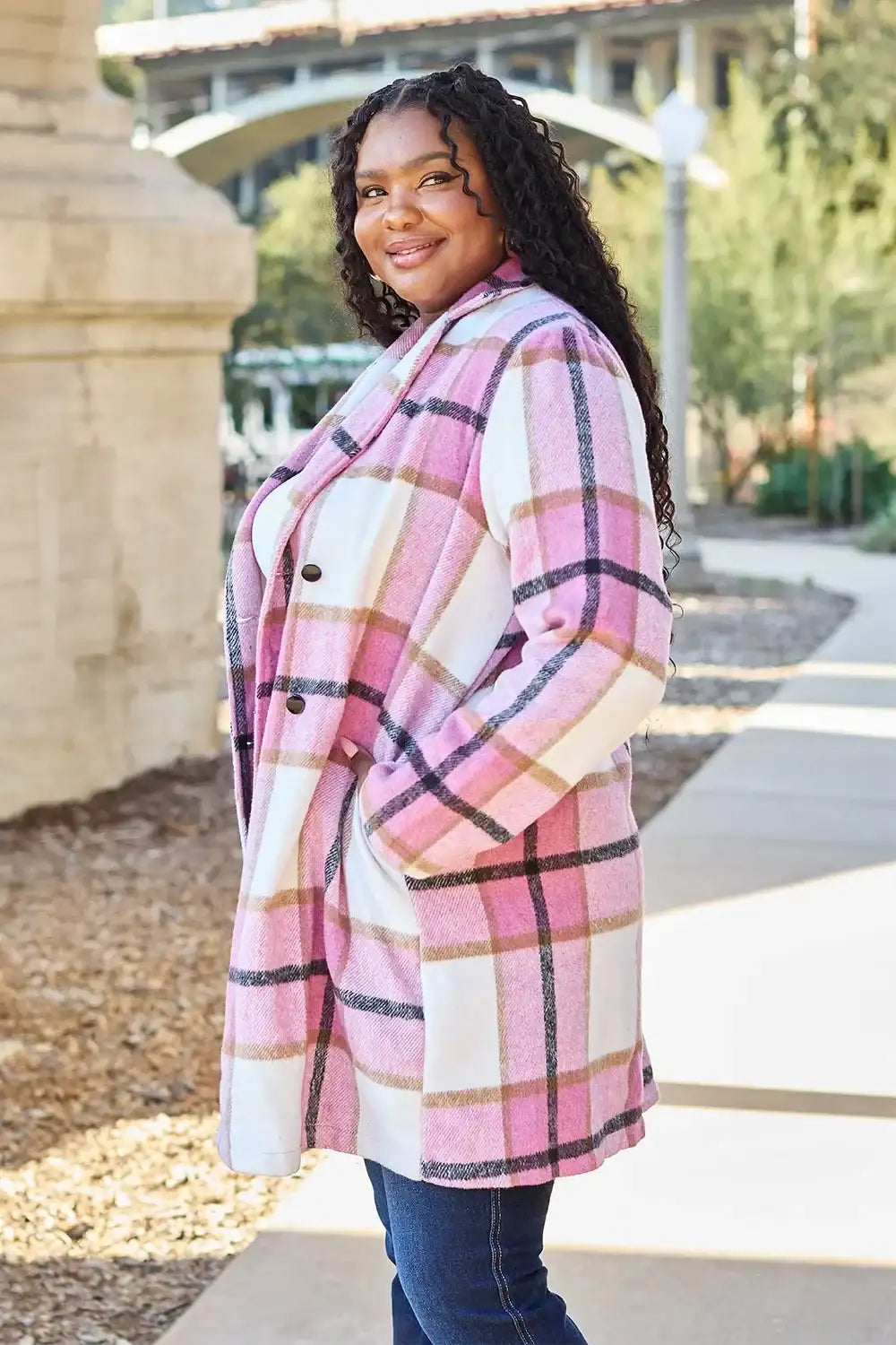 Woman wearing a pink plaid coat standing outdoors.