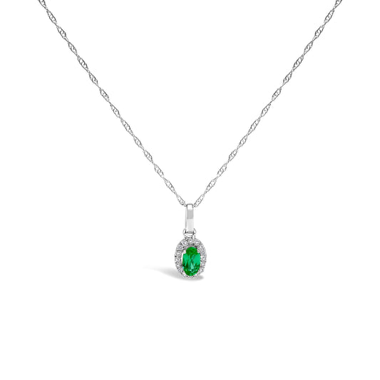 10K white gold pendant necklace featuring a 5x3mm green emerald surrounded by diamond accents on an 18" chain.