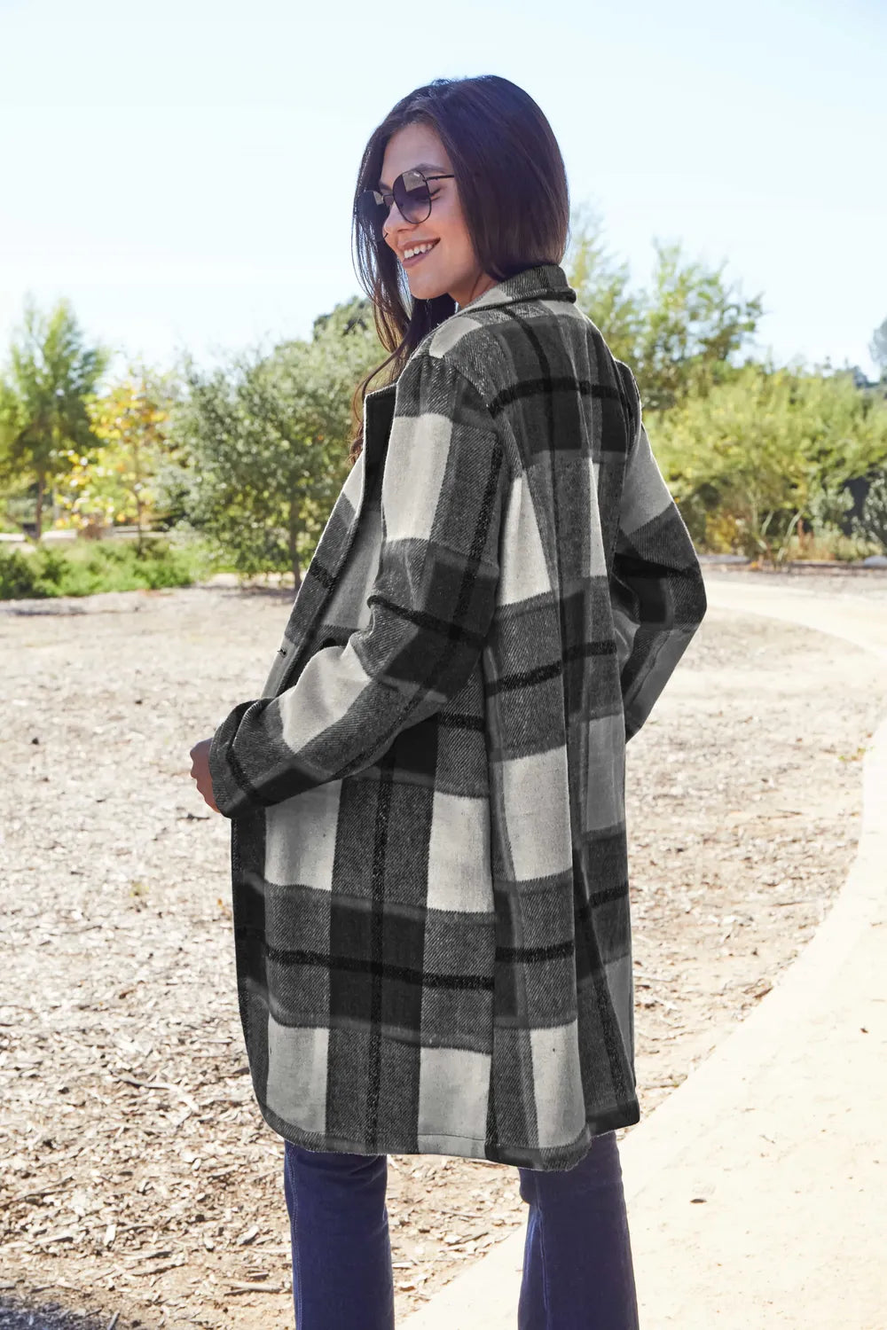 Woman wearing a plaid coat outdoors on a sunny day