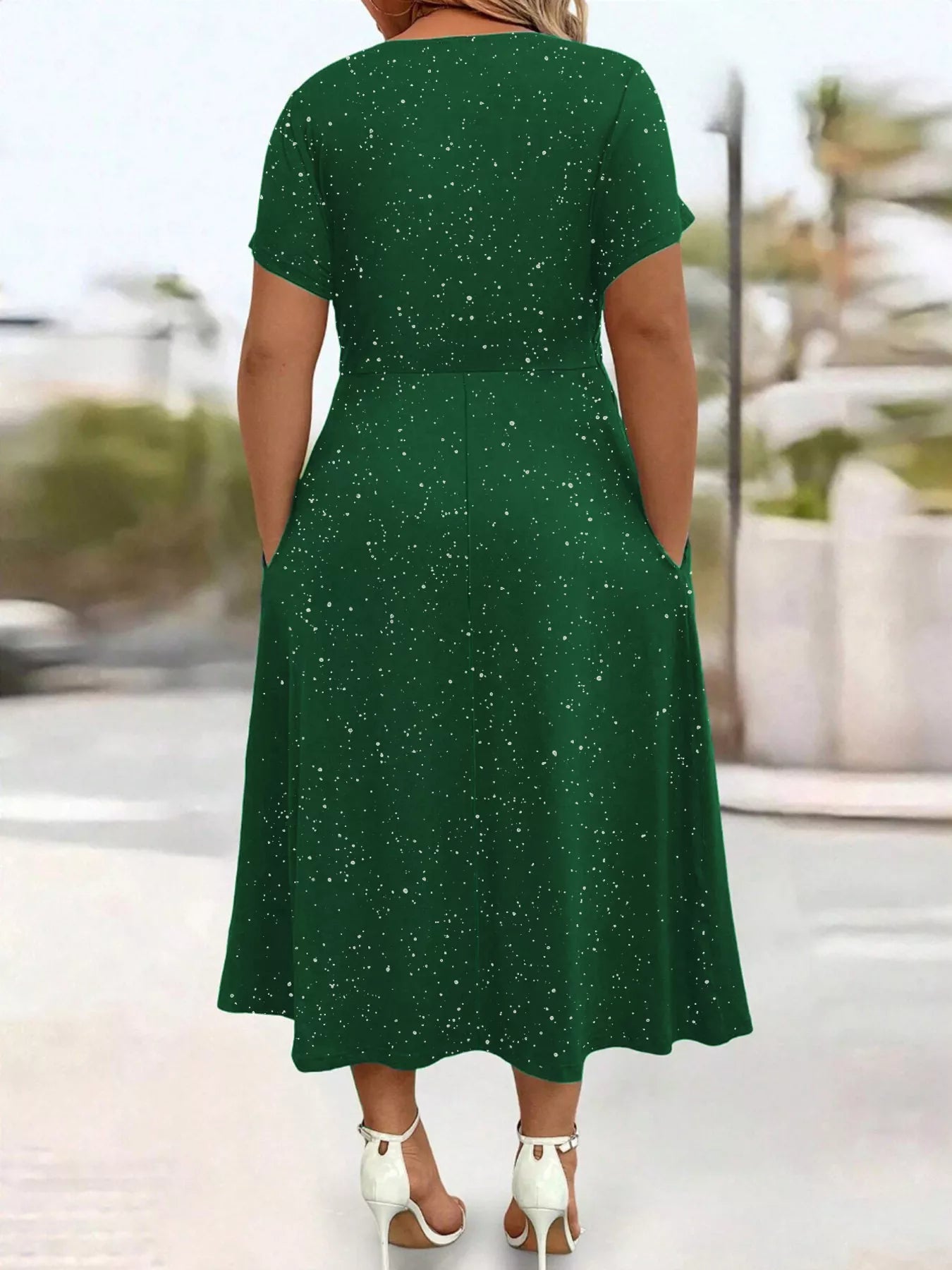 Green dress with white speckles worn by a person, blurred outdoor background