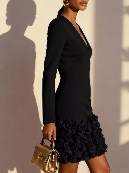 Woman wearing a black dress with floral details, holding a gold handbag against a neutral background