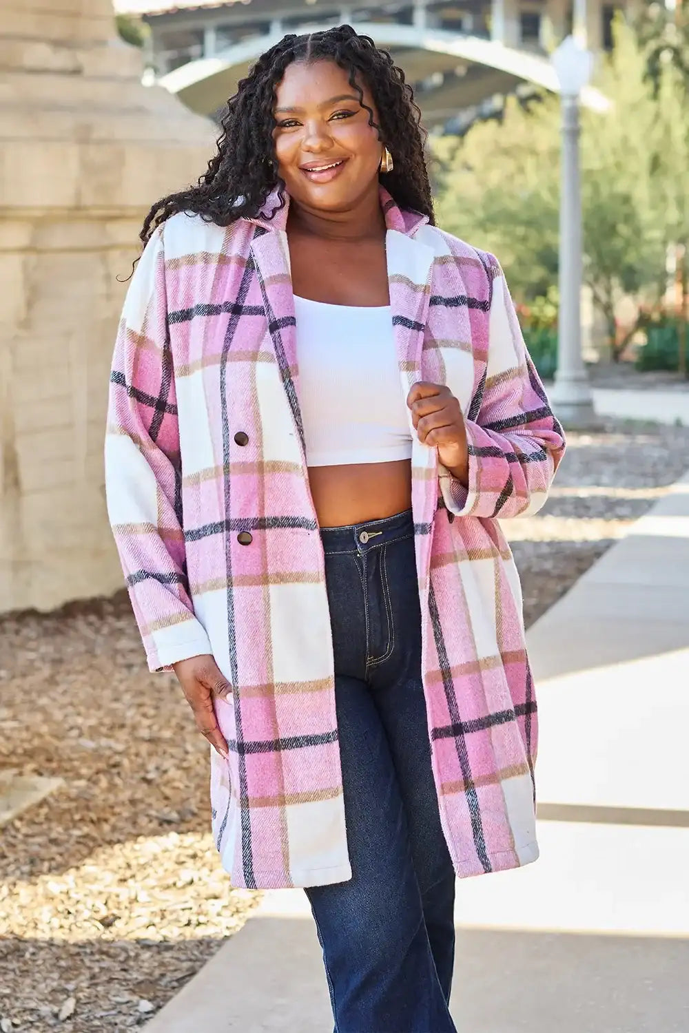 Woman wearing a plaid coat standing outdoors on a sunny day.