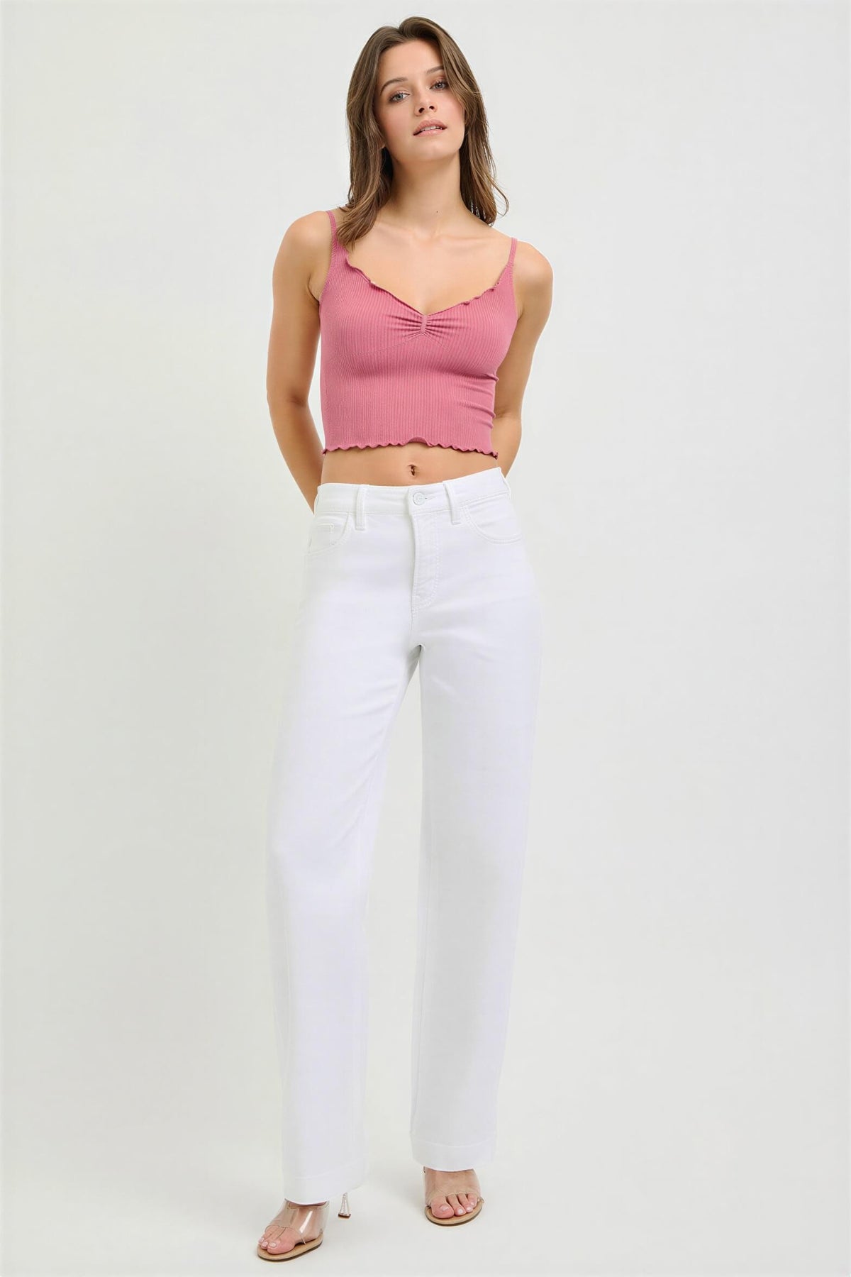 Woman wearing a pink top and white pants on a white background