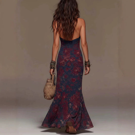 Back view of a woman in a blue and red floral print mermaid maxi dress holding a woven straw bag.