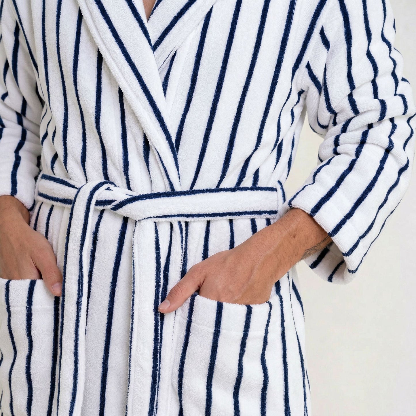 Person wearing a white robe with blue stripes on a plain background