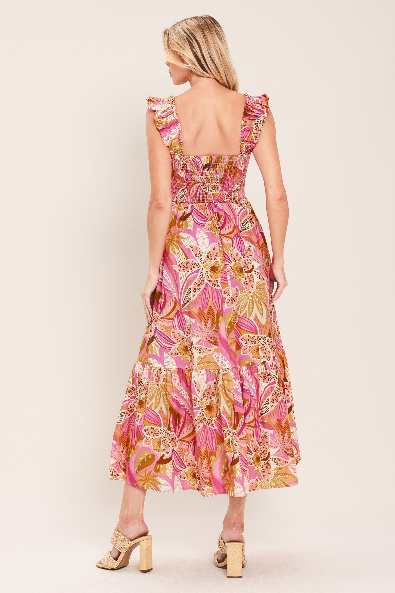 Woman wearing a pink and gold floral dress on a white background