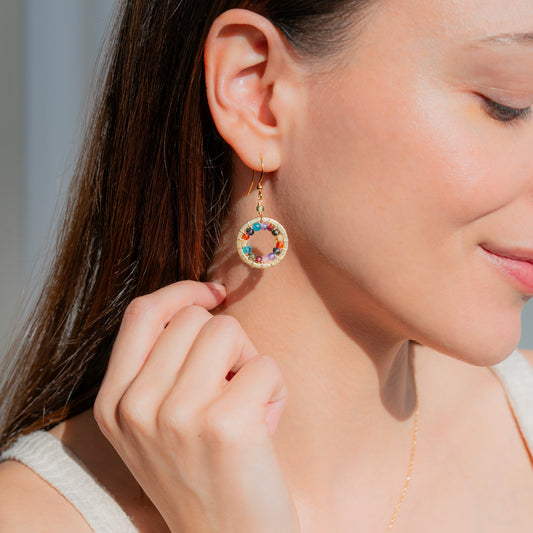 Close-up of a woman wearing colorful earrings with a neutral background