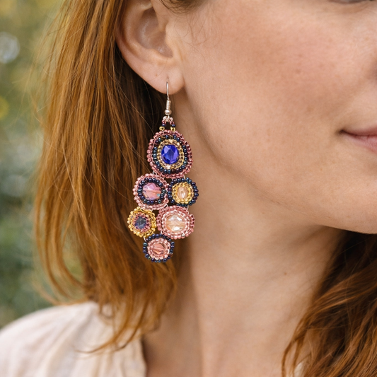 Close-up of a person wearing colorful earrings with a blurred background