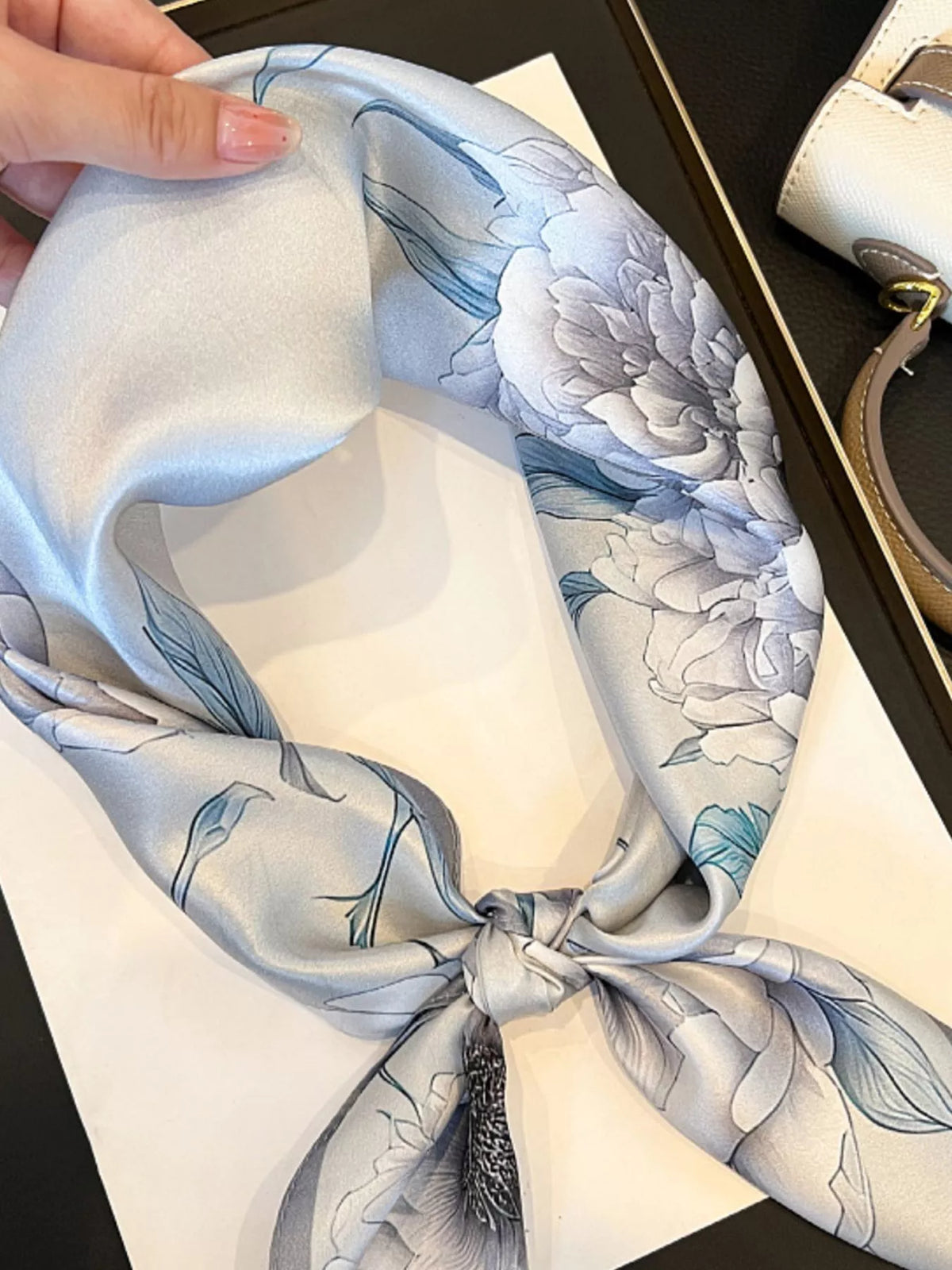 Woman styling a floral silk scarf as a neck tie accessory