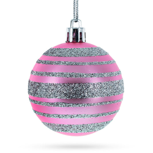 One round pink plastic ornament with horizontal silver glitter stripes hanging from a silver string.