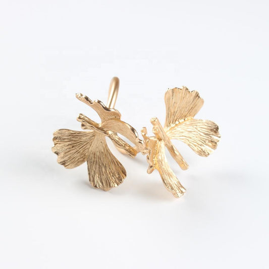 Gold leaf-shaped earrings on a white background