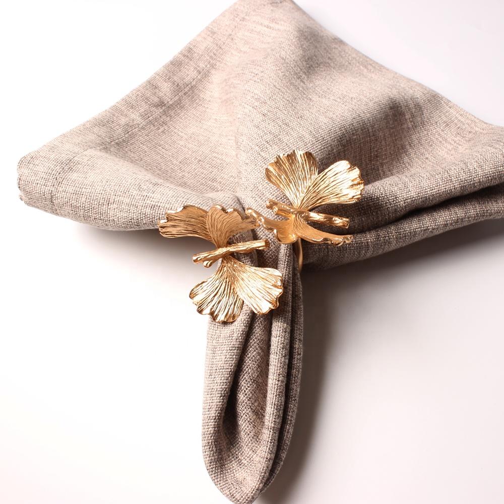 Gold leaf napkin holder on a beige napkin against a white background