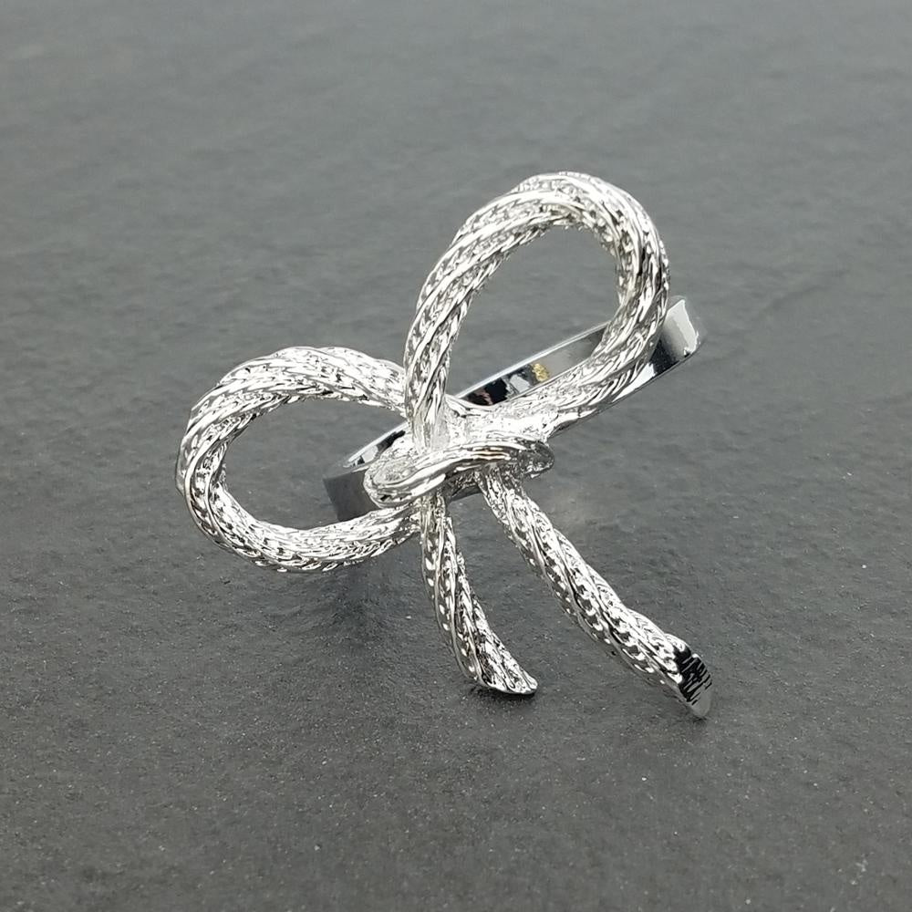 Silver bow-shaped brooch on a dark gray background