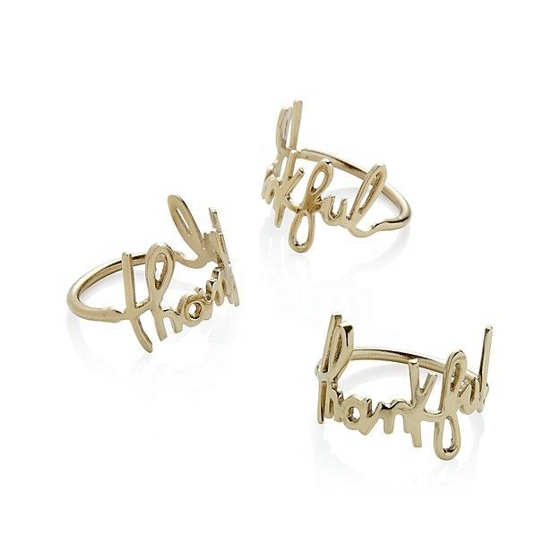 Three gold rings with cursive text on a white background