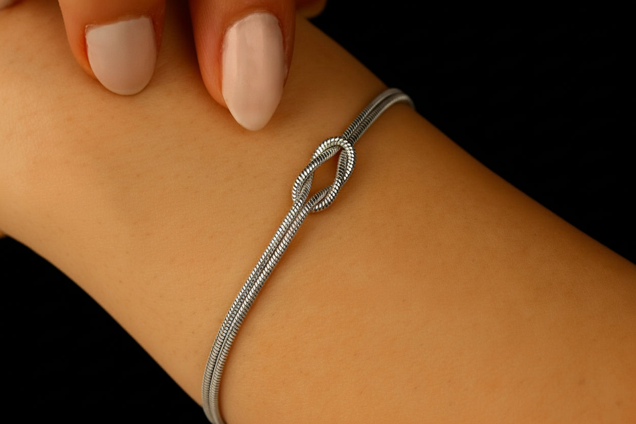 Silver Lush Love Knot bracelet on a wrist, featuring a sleek design in 925 sterling silver with a twisted knot detail.