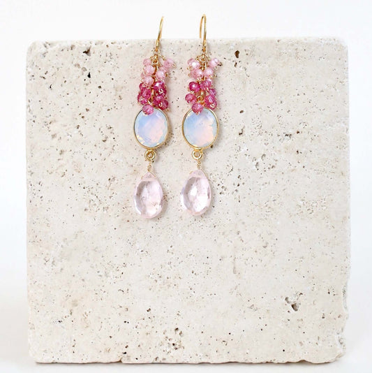 Pair of pink and gold earrings on a textured white surface