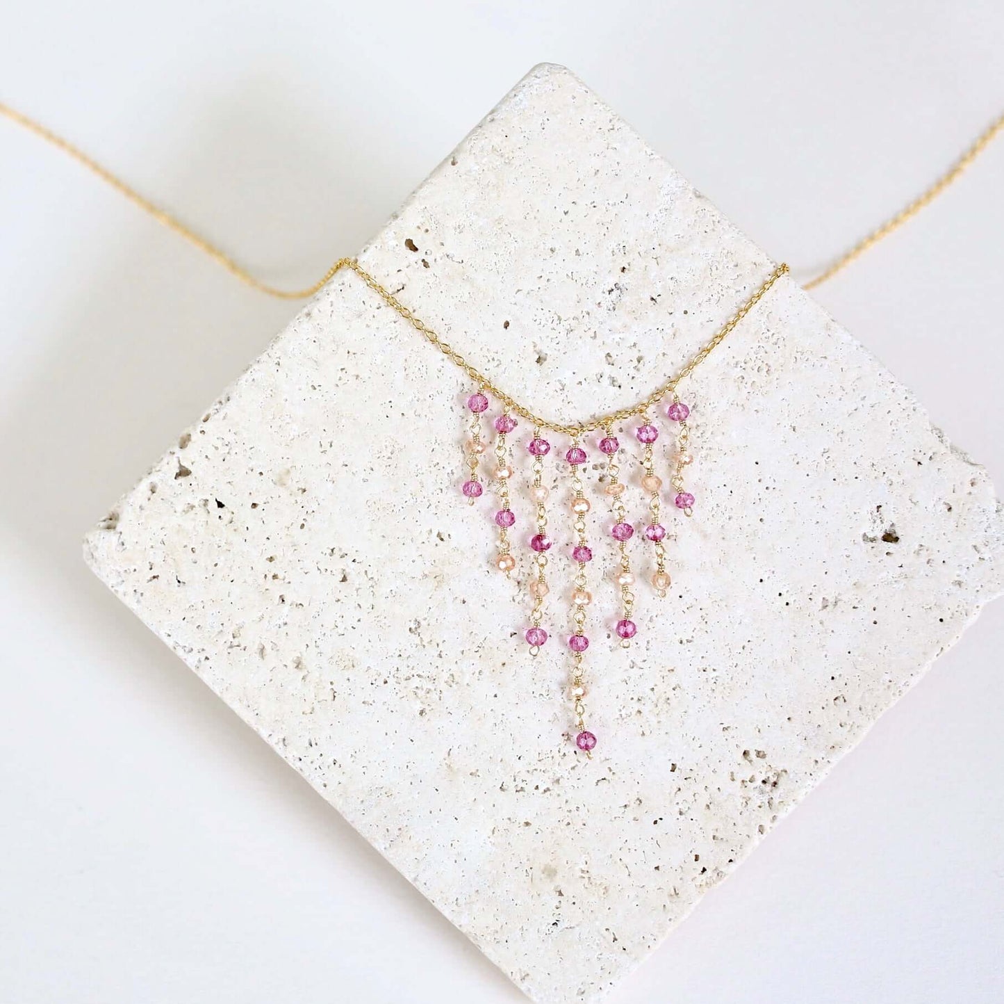Necklace with pink beads on a textured white surface
