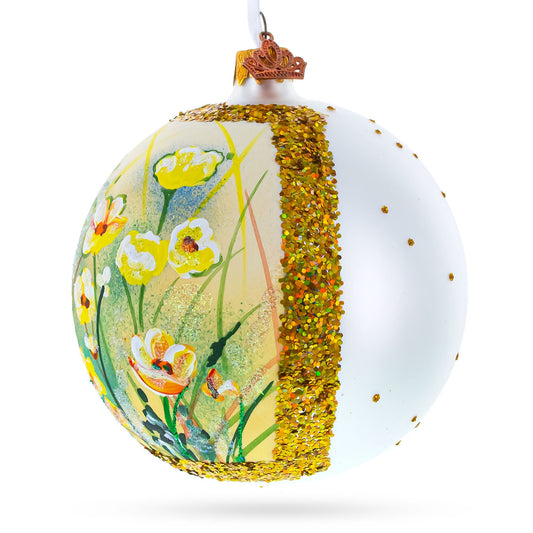 Round white glass ornament featuring a hand-painted yellow floral scene and a vertical band of gold glitter.
