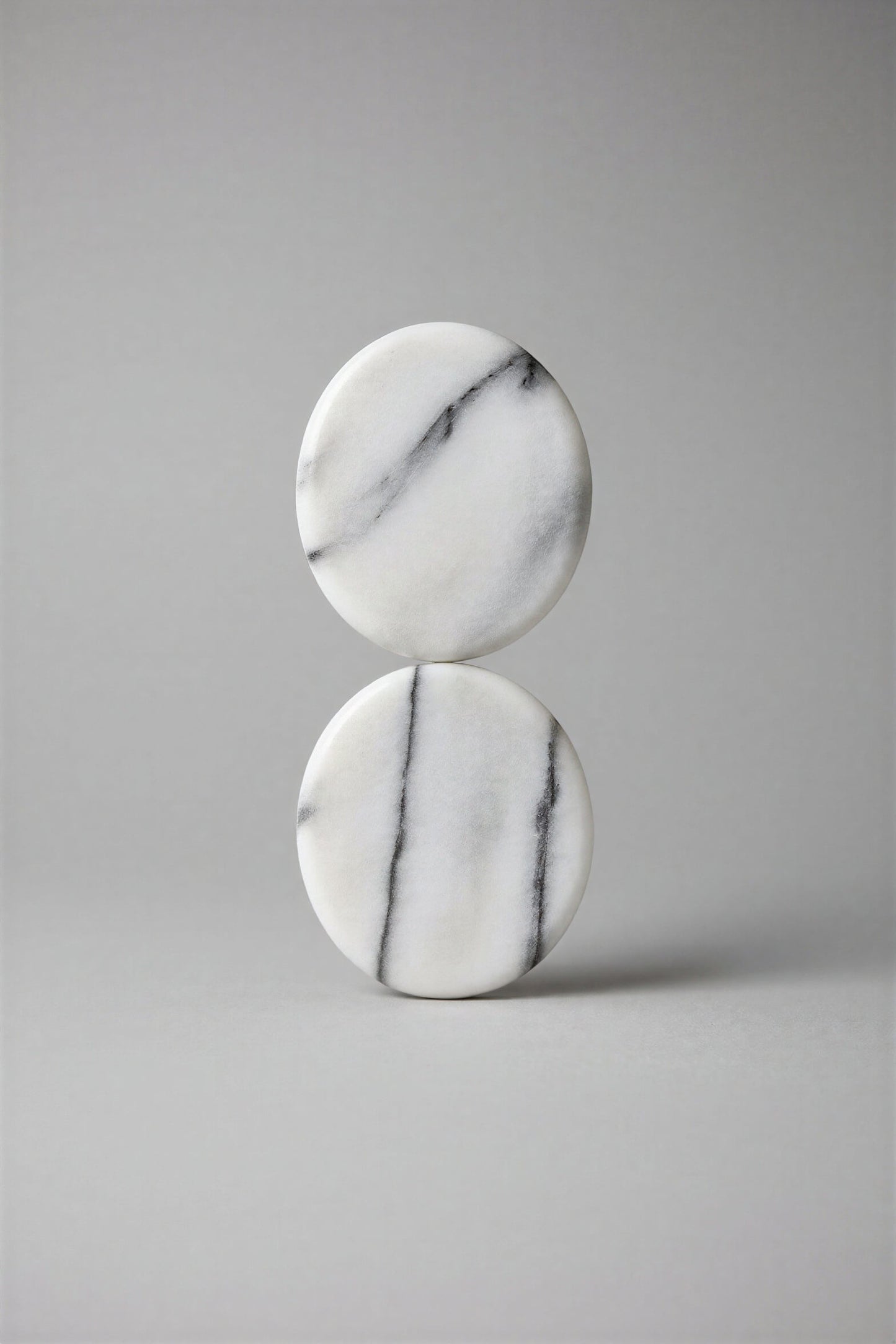 Two smooth polished oval stones with natural gray veining on a blue and green striped textured background.