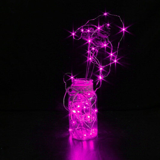 Pink LED string lights inside a clear glass jar on a black background