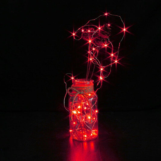 Decorative jar with red string lights on a black background