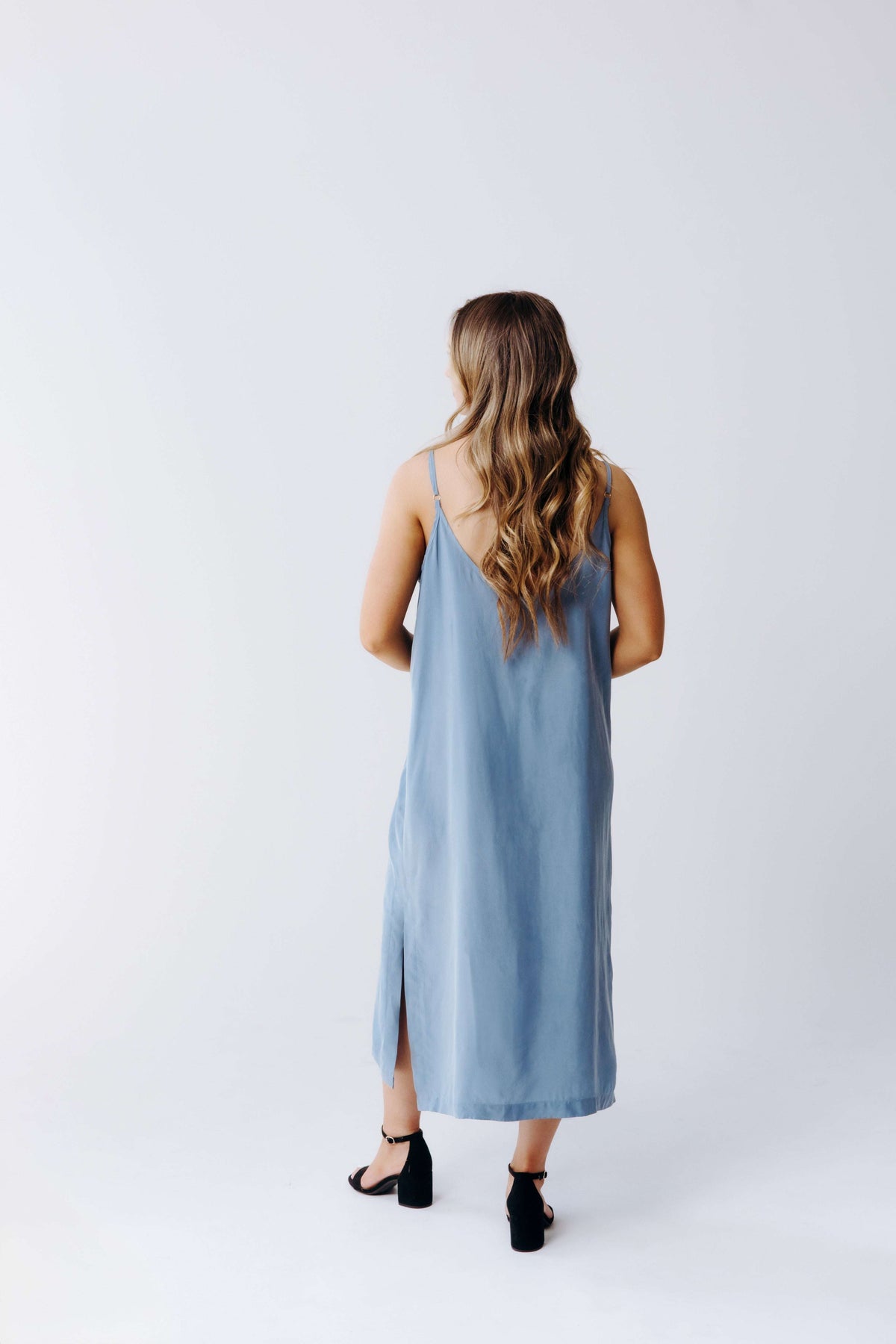 Woman wearing a light blue sleeveless dress on a white background