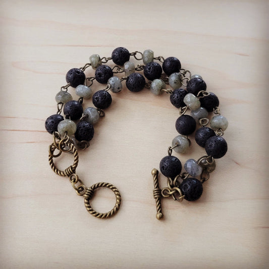 Bracelet with black and gray beads and bronze clasp on a light wood surface