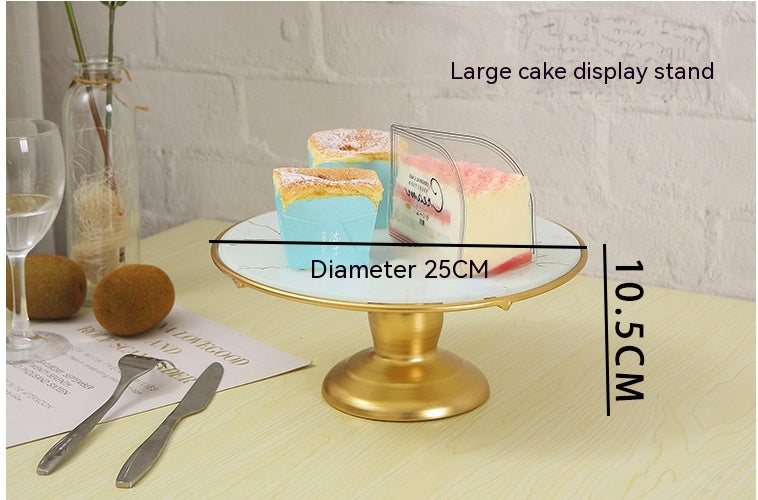 Gold cake stand with a cake on a table, showing dimensions.