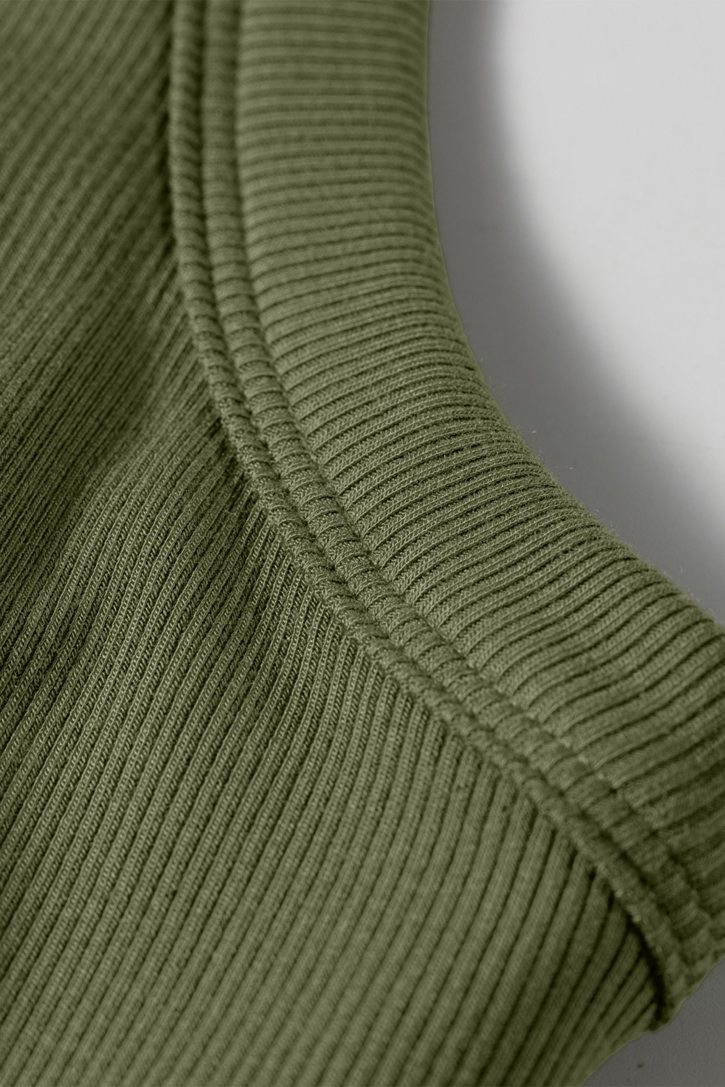 Close-up of a green ribbed sweater sleeve on a white background