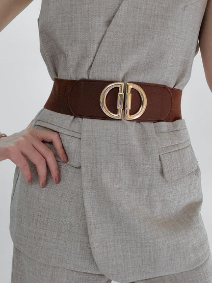 Person wearing a gray outfit with a brown belt and gold buckle on a plain background