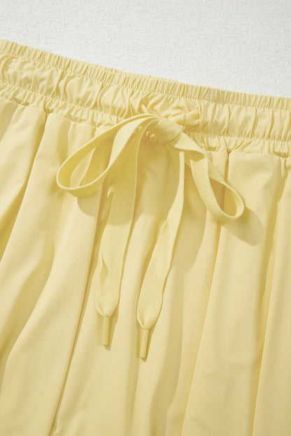 Close-up of pale yellow drawstring shorts showing the elastic waistband and tie detail.