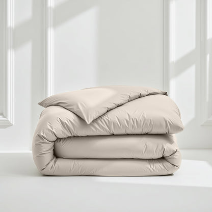 Beige comforter folded neatly on a white surface with a light gray wall background