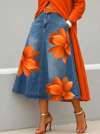Person wearing an orange top and blue denim skirt with floral patterns against a gray background