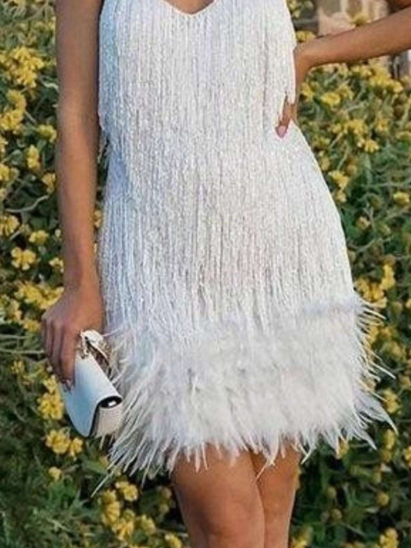 Person wearing a white fringe dress with a blurred natural background