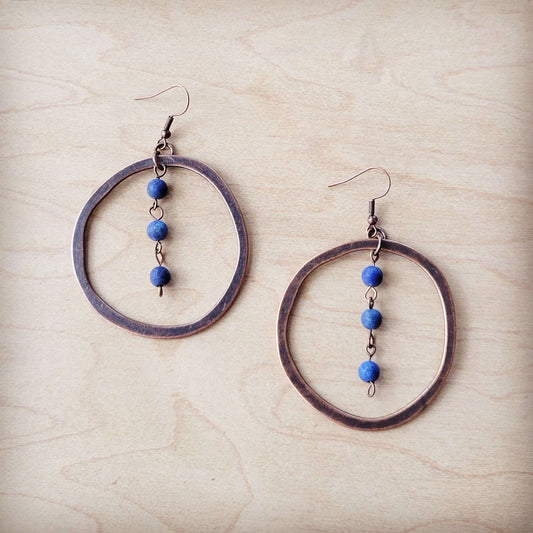 Pair of hoop earrings with blue beads on a beige surface