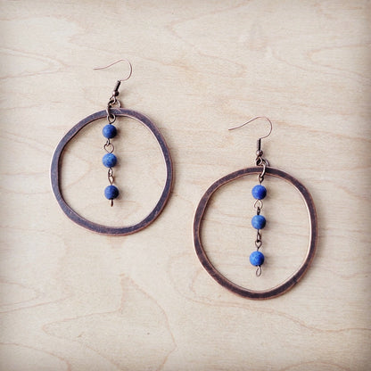 Pair of hoop earrings with blue beads on a beige surface