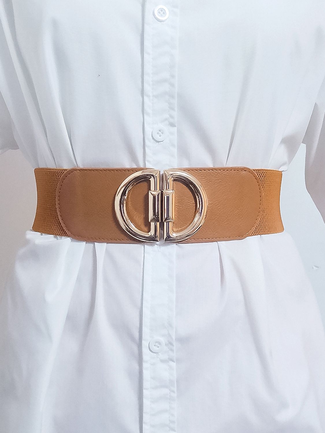 Tan belt with a large gold buckle worn by a person wearing a white shirt.