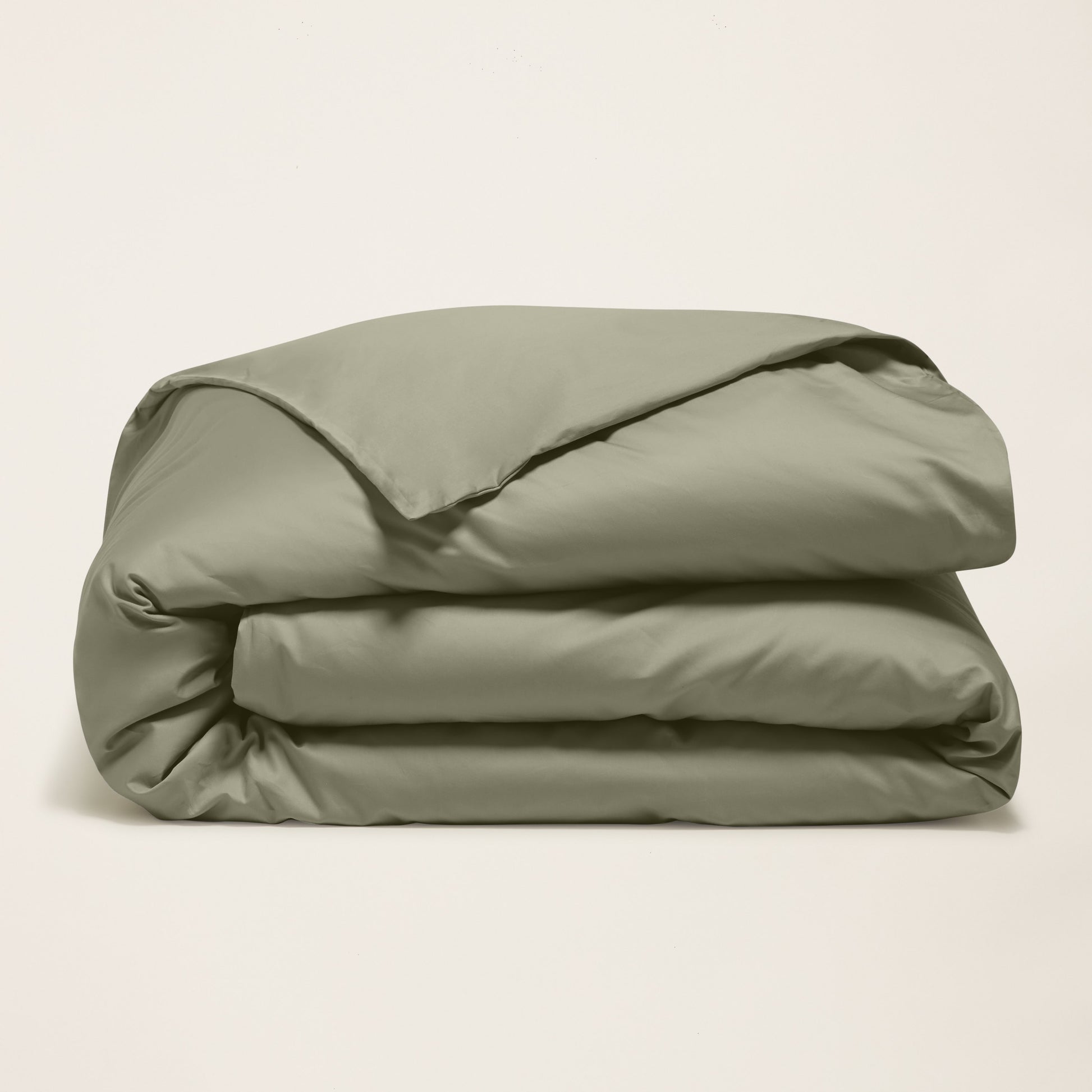 Folded beige comforter on a light beige background