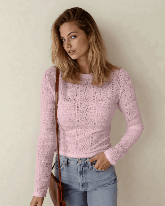 Woman wearing a pink knitted sweater and blue jeans against a plain background