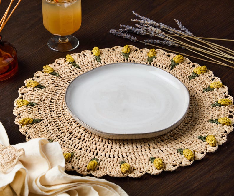 Handmade tulip placemat with raffia crochet, featuring yellow floral accents, set on a dark wooden table.