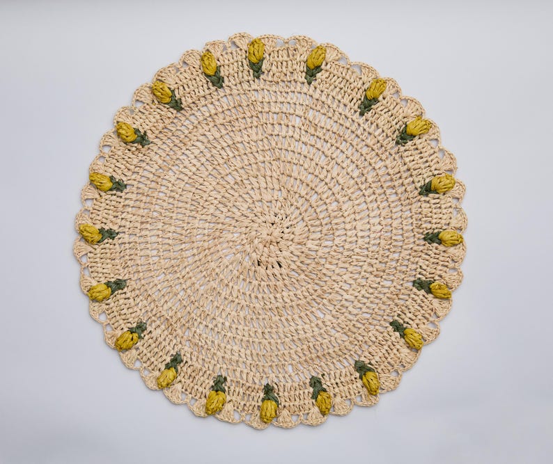 Handmade raffia crochet placemat featuring yellow tulip accents, round shape, ideal for spring and Easter table decor.