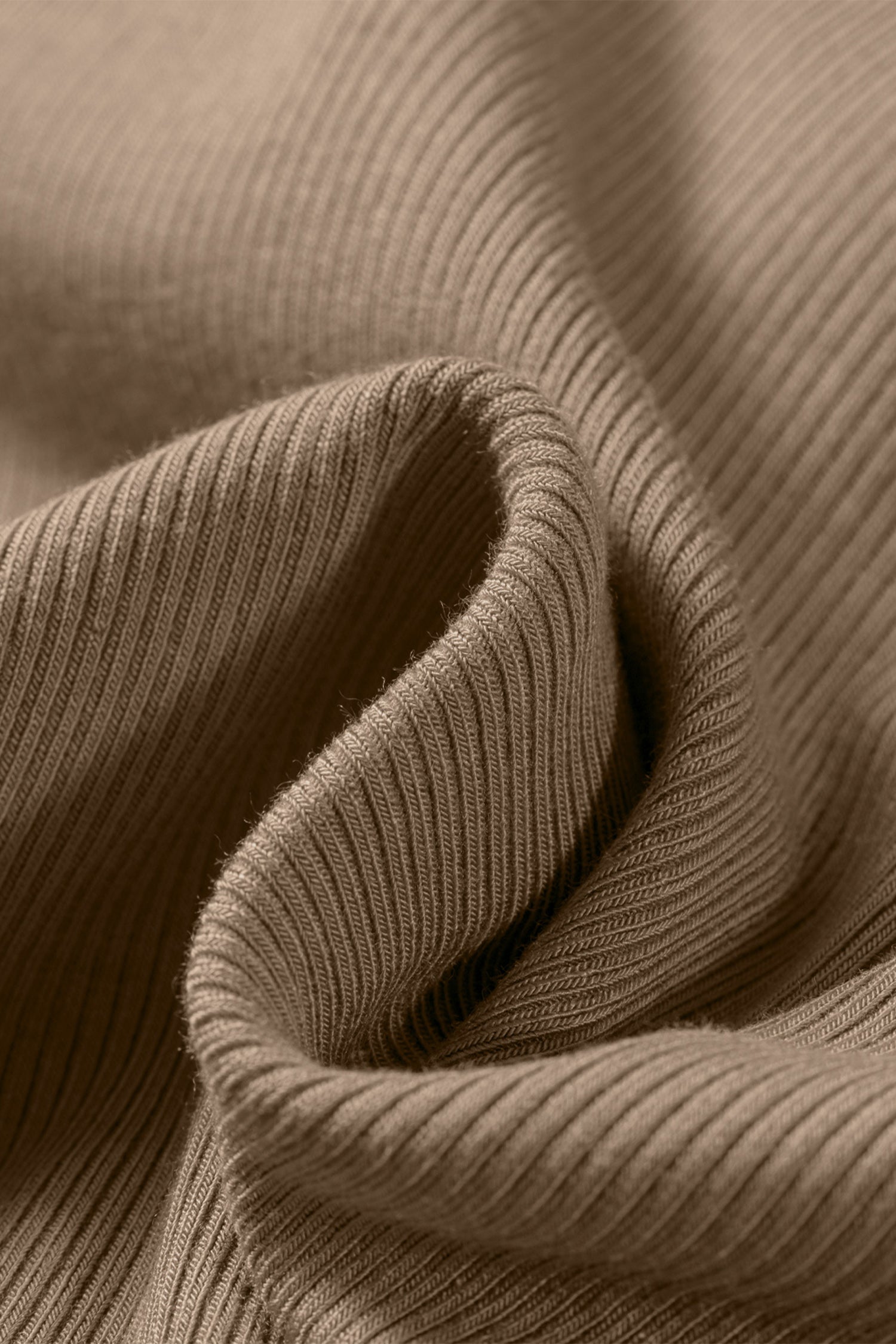 Close-up of folded tan ribbed fabric showing the vertical texture of the Slim Ribbed Padded Tank Top.