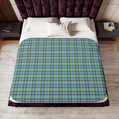 A bed dressed in white linens and a blue, green, and yellow plaid blanket, styled in a bedroom with a purple velvet headboard and nightstands.