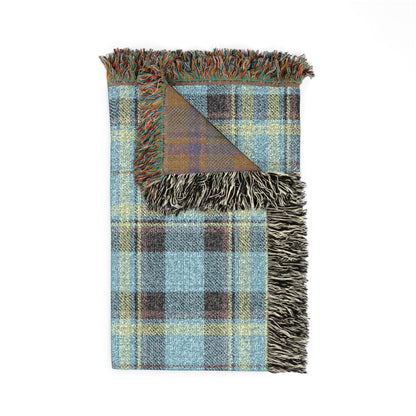A folded plaid throw blanket with fringed edges, featuring a pattern of light blue, brown, yellow, and gray stripes, shown on a plain white background.
