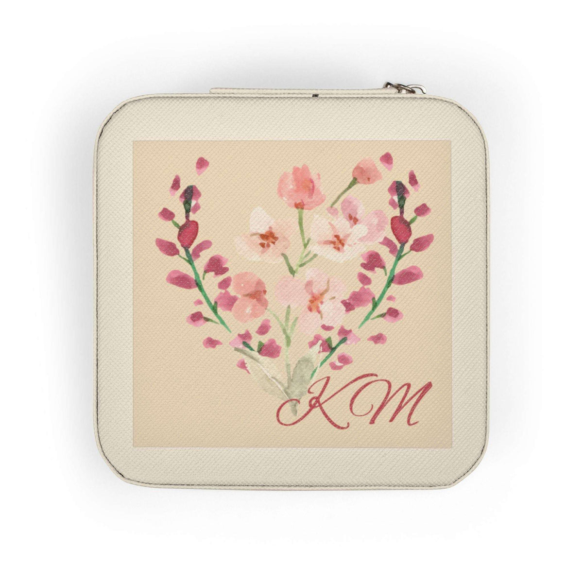 A square zippered pouch with rounded corners, featuring a cream-colored textured exterior and a central printed illustration of pink and white flowers arranged in a heart shape with the initials 'KM' in red script on a beige background.