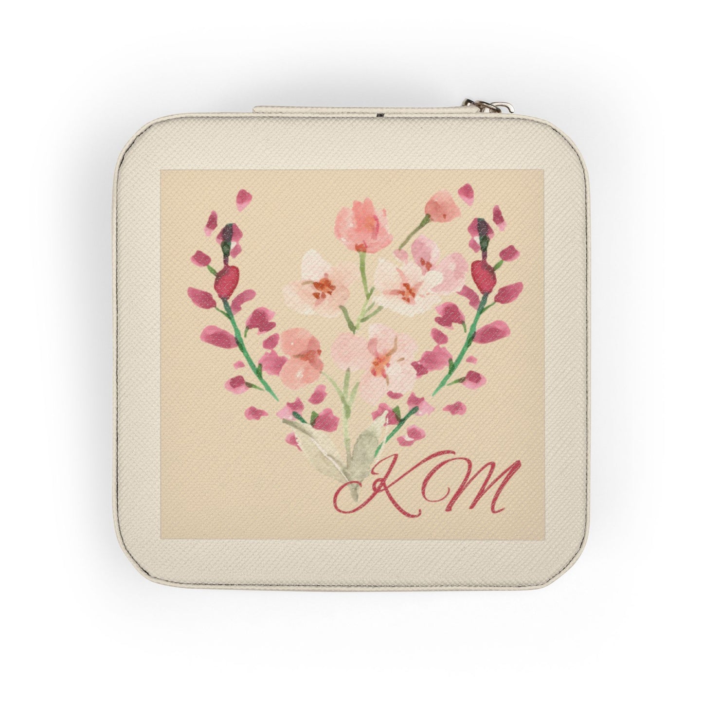 A square zippered pouch with rounded corners, featuring a cream-colored textured exterior and a central printed illustration of pink and white flowers arranged in a heart shape with the initials 'KM' in red script on a beige background.