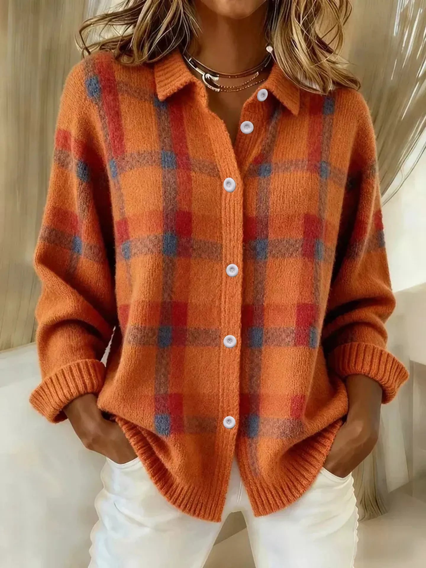 Person wearing an orange plaid cardigan with a neutral background