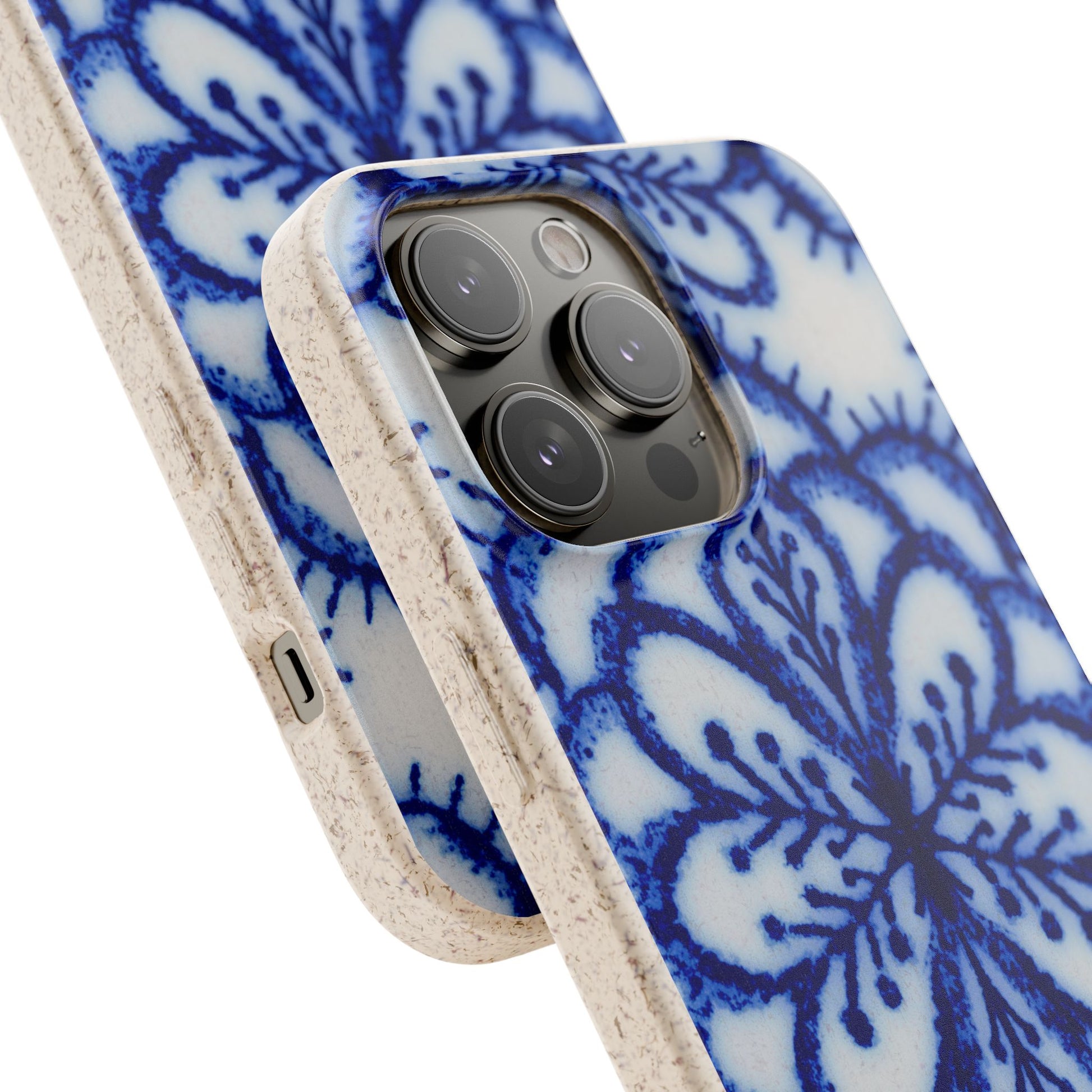 A close-up of a smartphone case with a blue floral mandala pattern on a white background and a textured beige bumper edge, shown fitted on a phone against a clean white background.